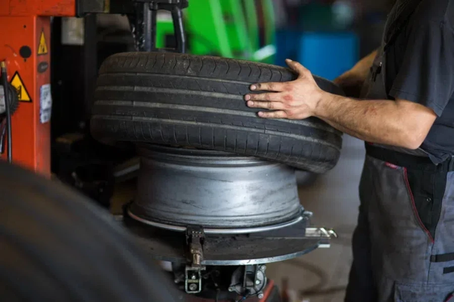 Tyre change - wheel balancing or repair and change car tire at auto service garage or workshop by mechanic