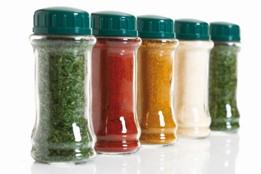 Variety of herbs and spices in glass jar on white background