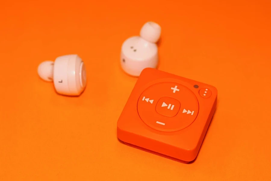 White Earphones Beside Orange Music Player