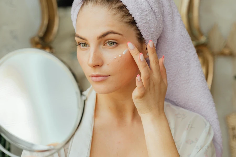 Woman Looking in the Mirror and Applying a Face Cream