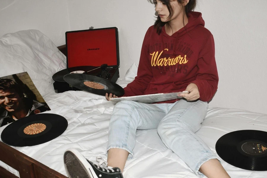 Woman Sitting on Bed Holding Vinyl Records