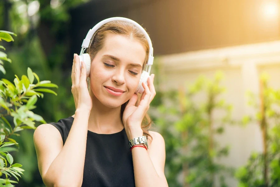 Woman Wearing Black Sleeveless Dress Holding White Headphone