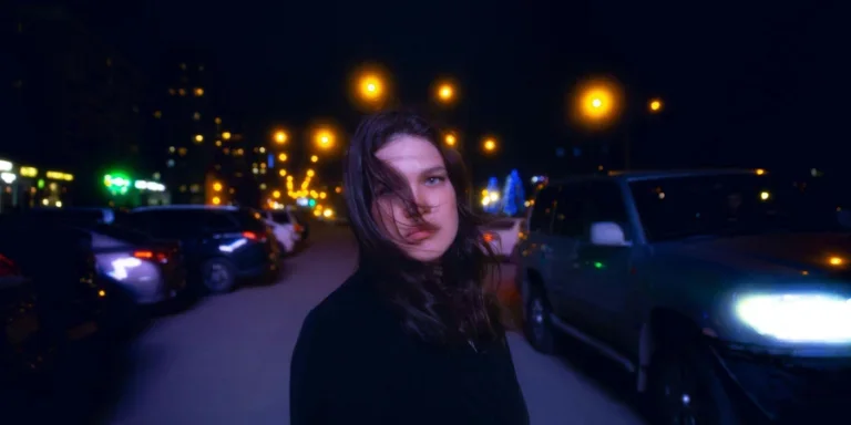 Женщина в черном пиджаке стоит на дороге