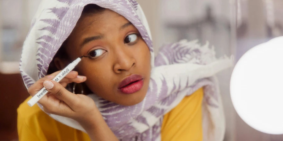 Woman in White and Purple Hijab Holding an Eyeliner