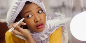 Wanita Berhijab Putih dan Ungu Memegang Eyeliner