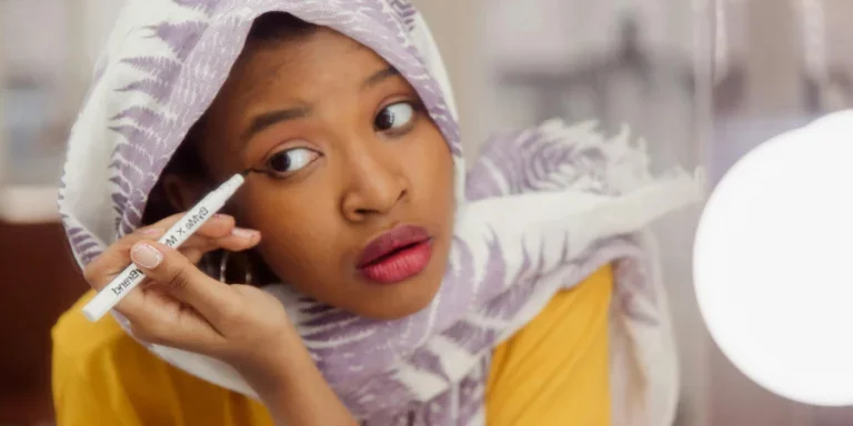 Mujer En Hijab Blanco Y Morado Sosteniendo Un Delineador De Ojos