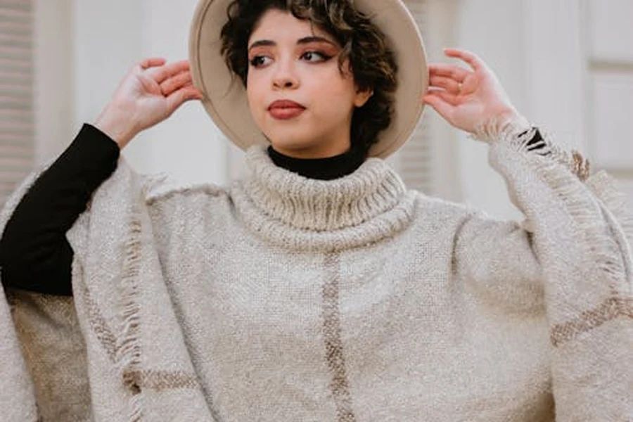 Woman in a short cream poncho with big collar and fringe