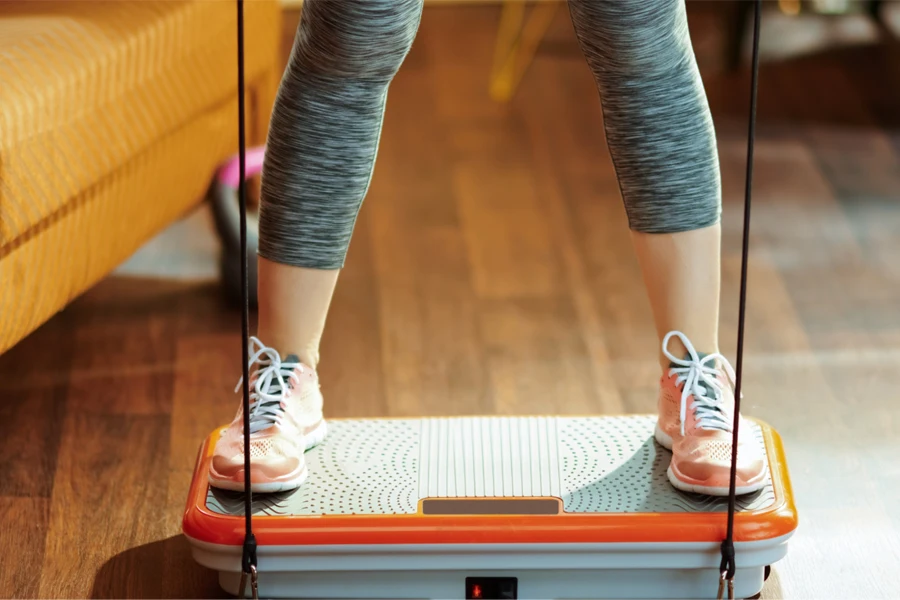 Woman in sneakers using a vibration plate