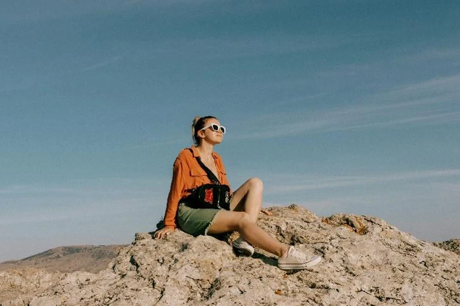 Woman posing on rock with graphic backpack