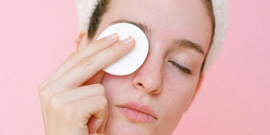 Woman removing eye makeup with cotton pad