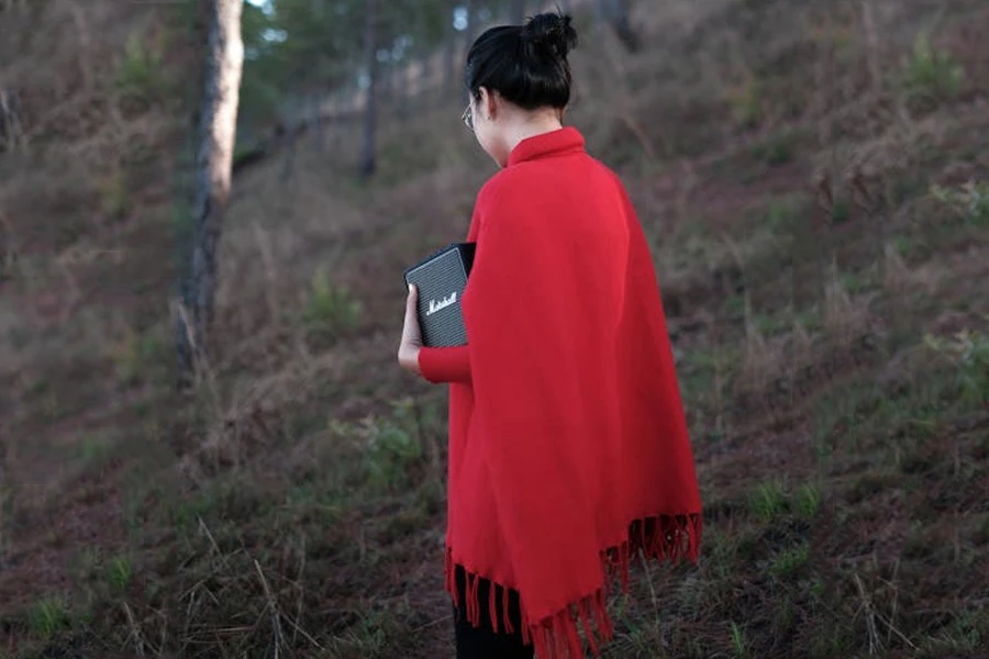 Woman wearing a knee-length red poncho with tassels