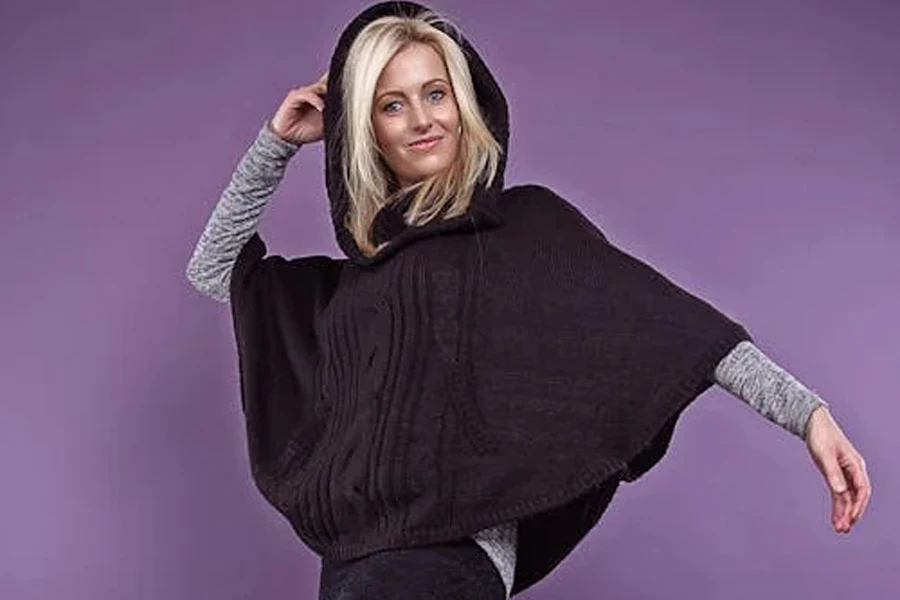 Woman wearing a short black poncho with a hoodie