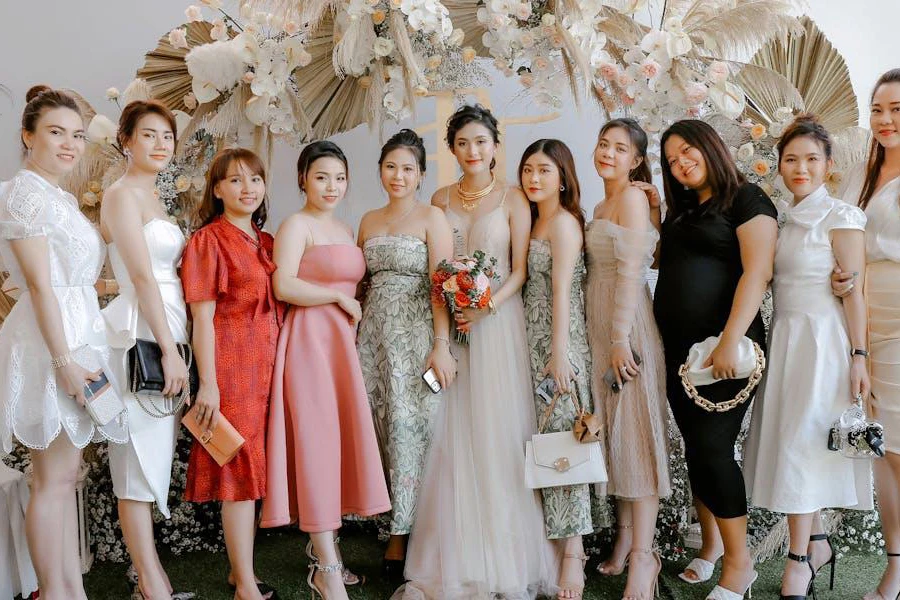 Women posing with the bride in different dresses