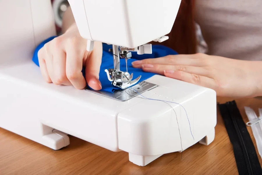 Young woman sewing fabric on sewing machine