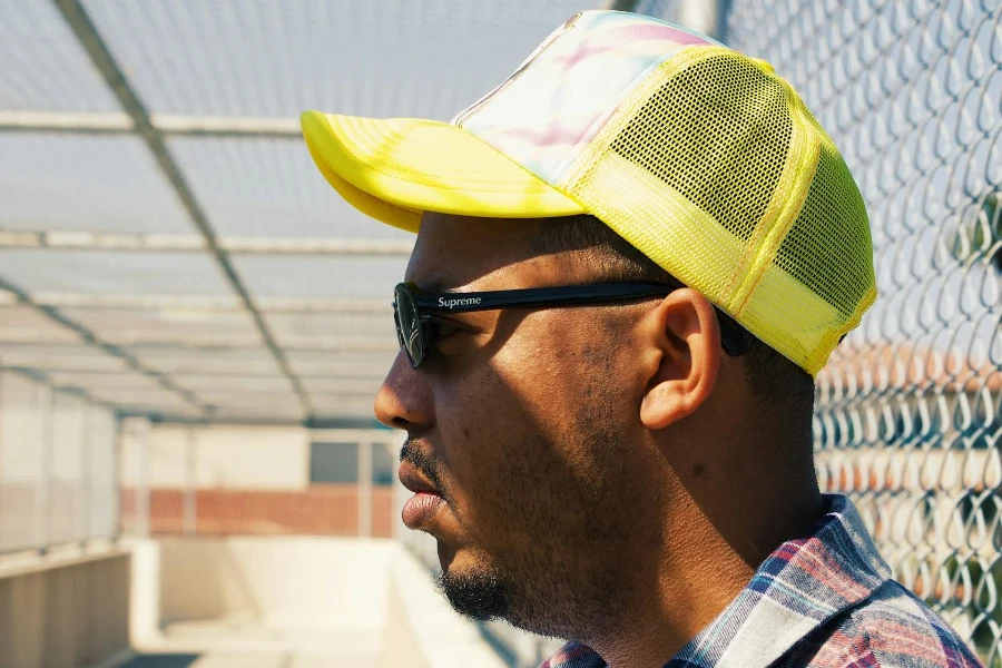 A man on glasses in a yellow trucker hat