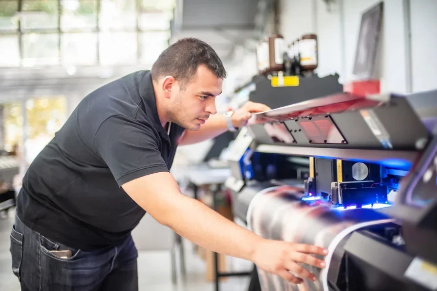 un tecnico esperto lavora su una stampante UV. Lavoro di produzione