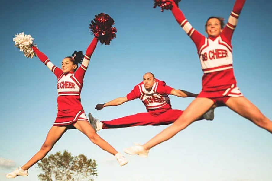 Cheerleaders jumping in the air with metallic pom poms