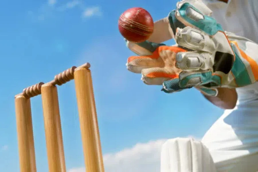 Cricket player catching the ball while wearing gloves