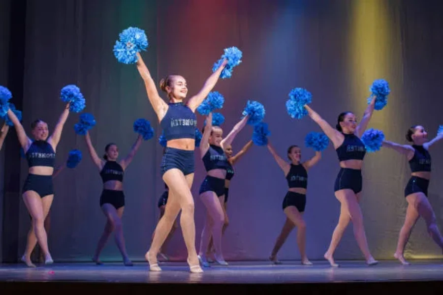 Girls performing cheer routine at indoor venue with pom-poms