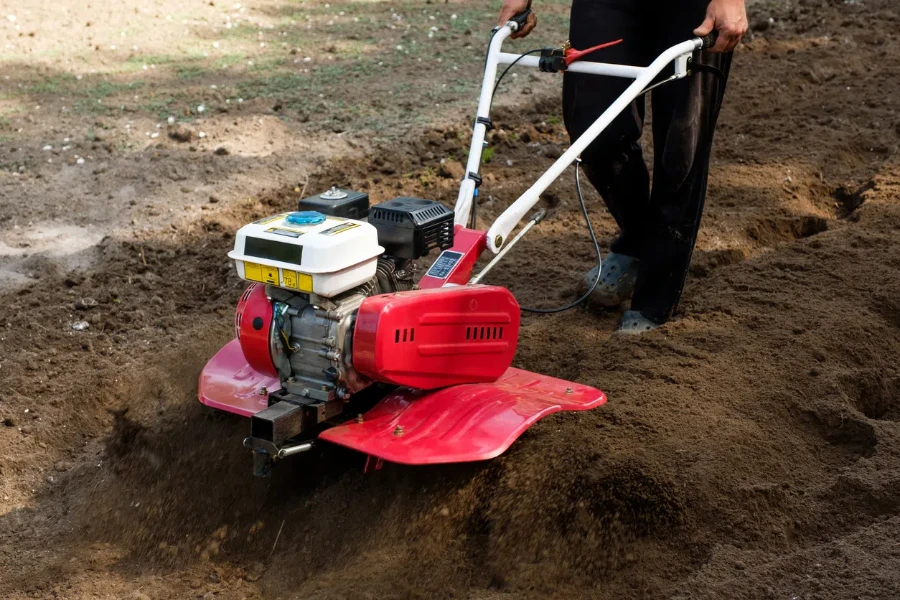 man working in the garden with garden tiller machine