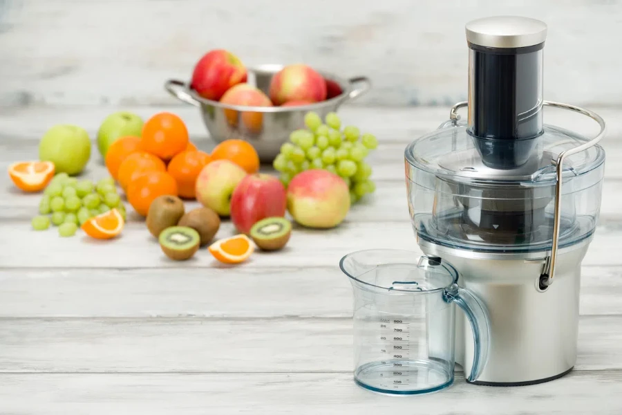 modern electric juicer and various fruit on kitchen counter