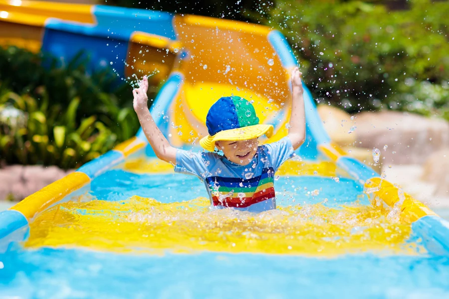 kids on water slide in aqua park. Children having fun on water slides on family summer vacation in tropical resort. Amusement park with wet playground for young child and baby