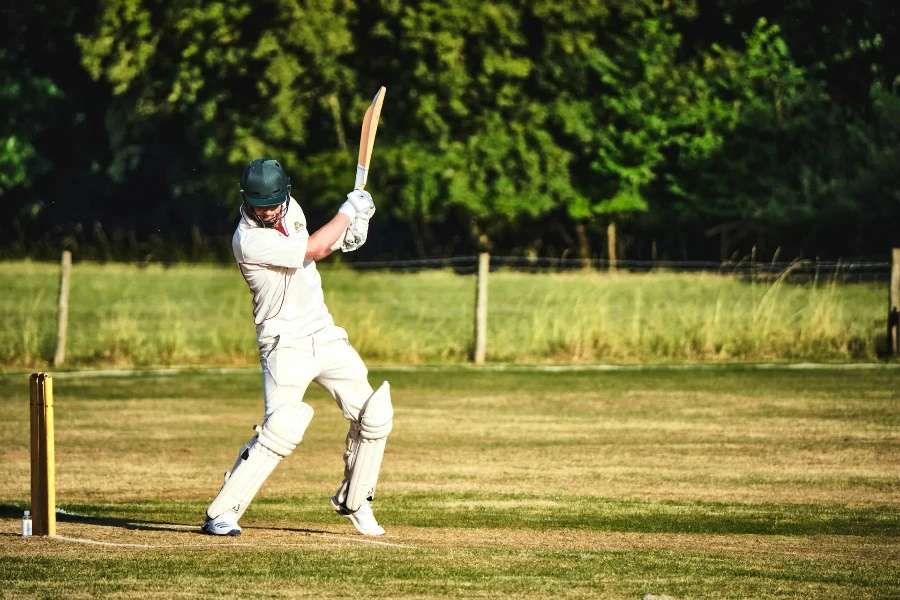 Male cricket player batting in front of wicket in sunshine