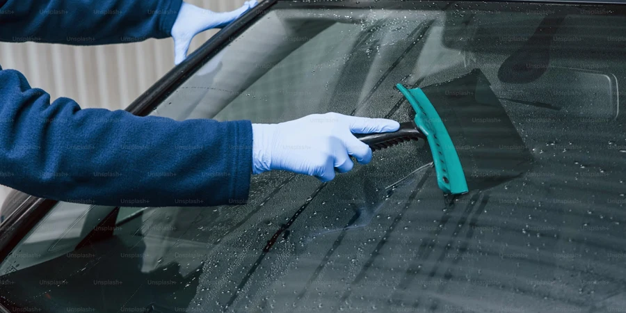 Trabajador masculino en uniforme lavando un auto nuevo y moderno, concepto de servicio