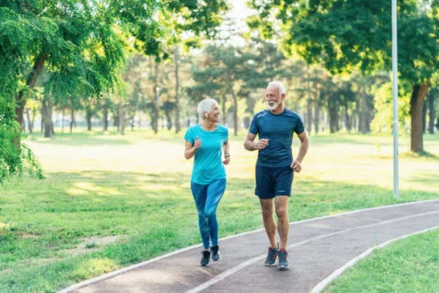 Man and woman jogging through park on track