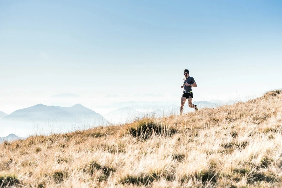 Man running down grassy hill in the mountains