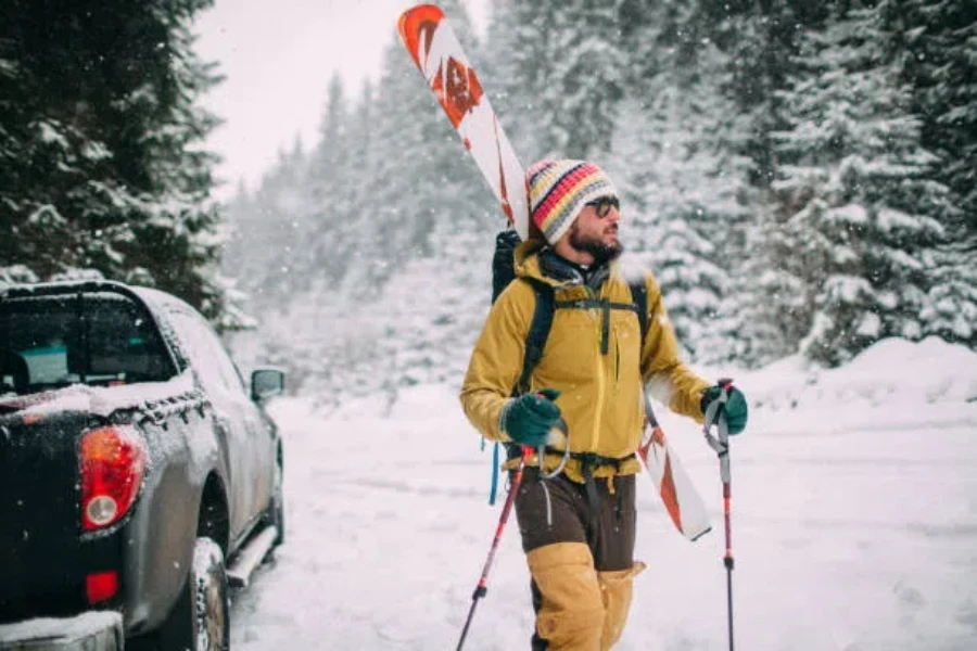 Man walking away from car with ski boot bag