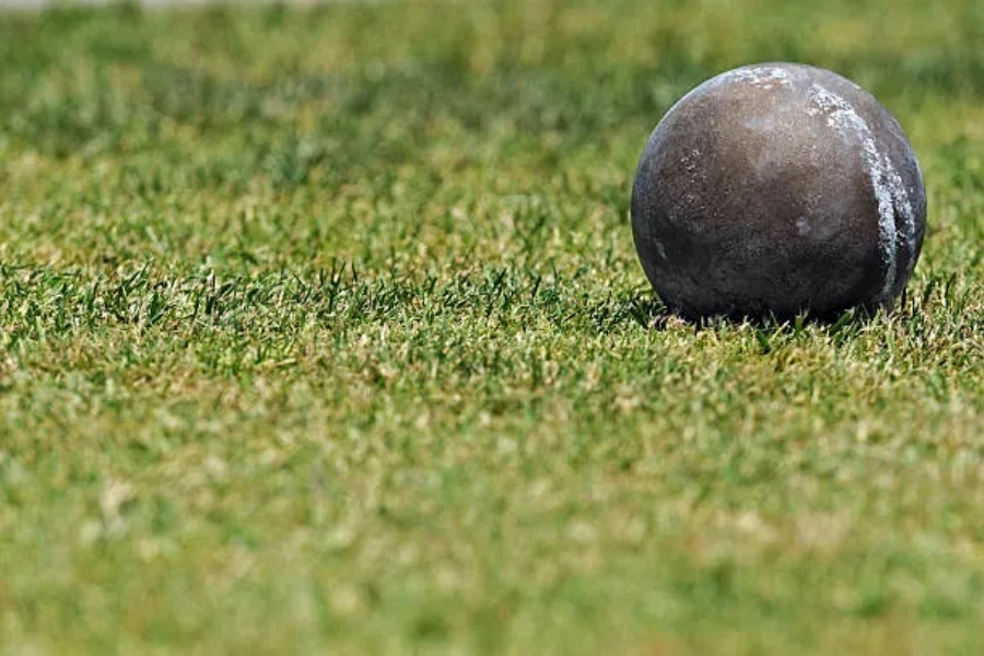 Metal shot put with chalk markings sitting on grass