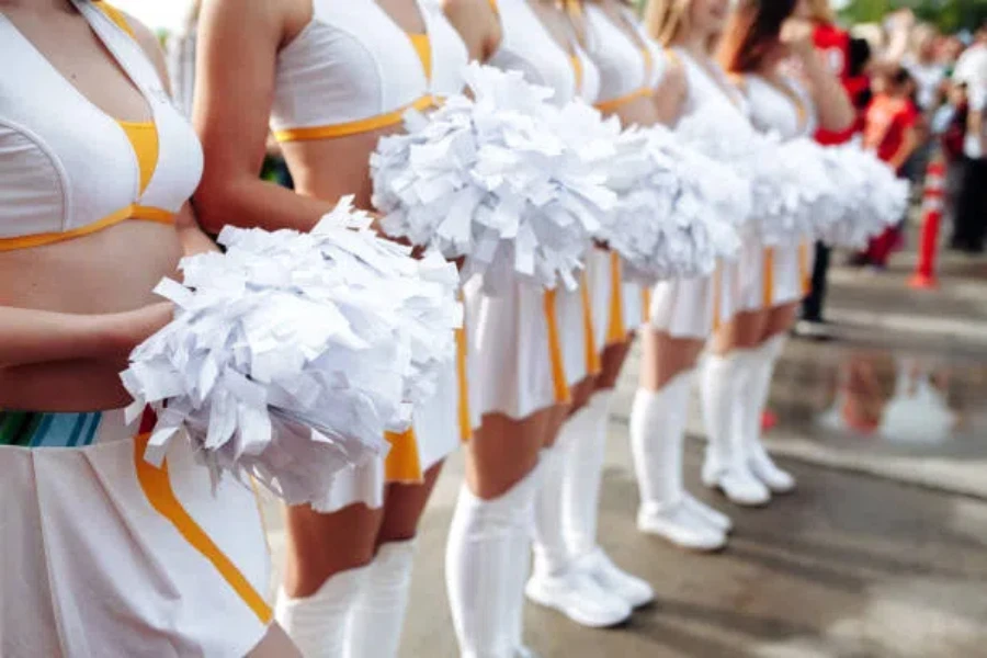 Row of cheerleaders holding pure white plastic pom-poms