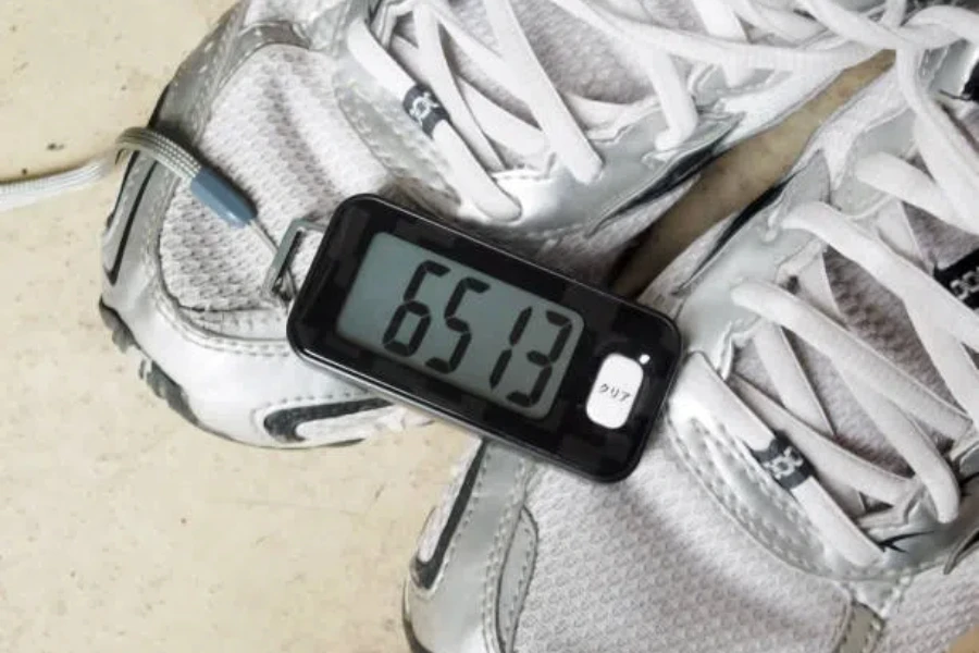 Small black pedometer with step count sitting on shoes