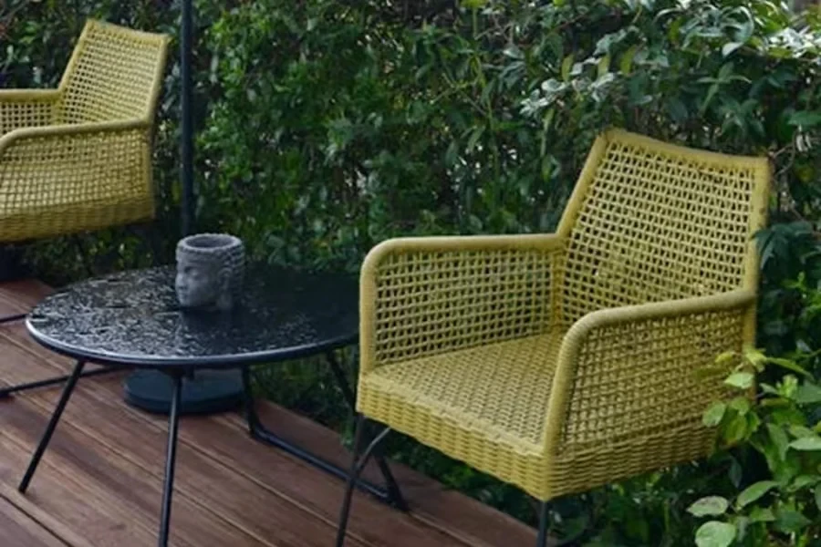 Two green rattan chairs on a deck with a table