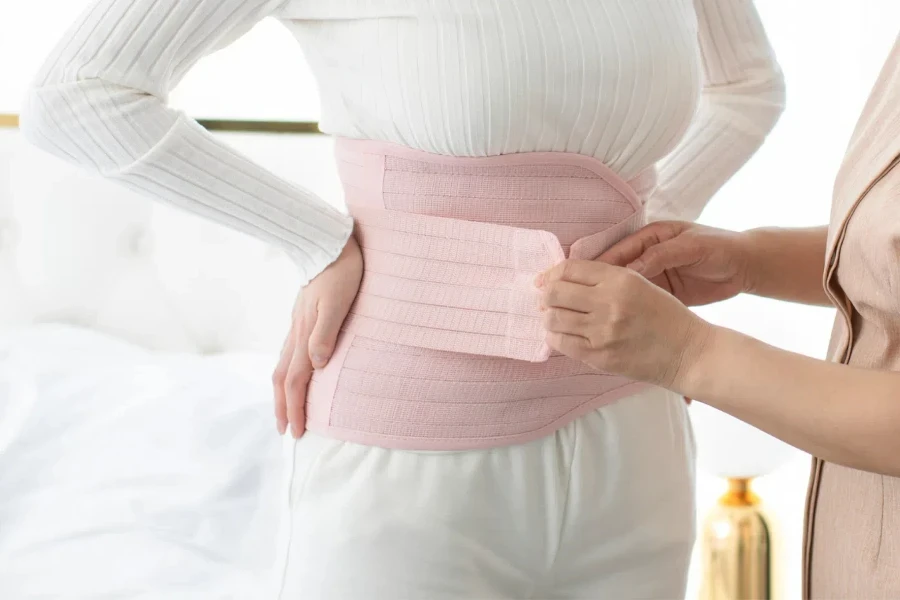 Woman trying to wear a pink waist trimmer