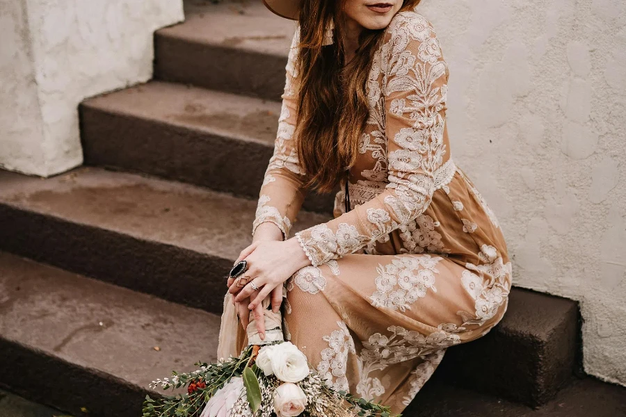 Woman wearing tan dress with white floral embroidery