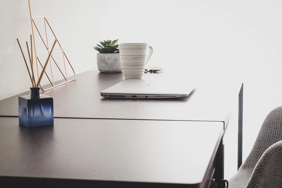 A diffuser placed on table along with a laptop and mug