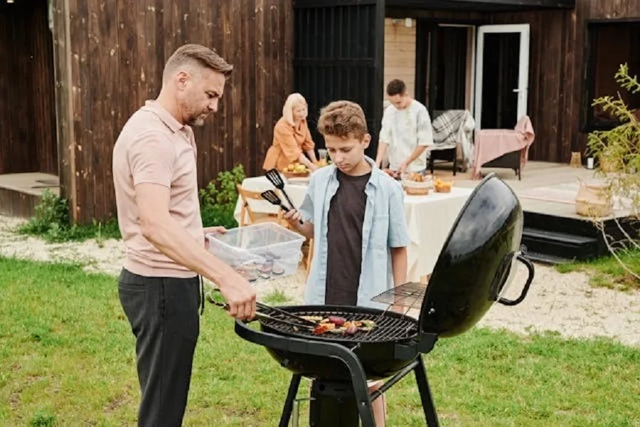 A man and a boy grilling in a backyard