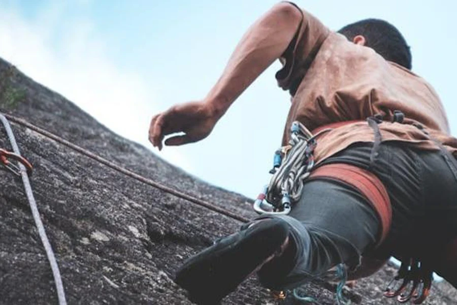 A man climbing a cliff with a harness and other equipment