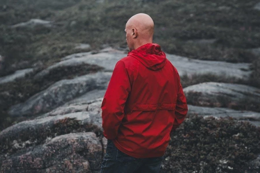 A man in a red windbreaker jacket on rocks