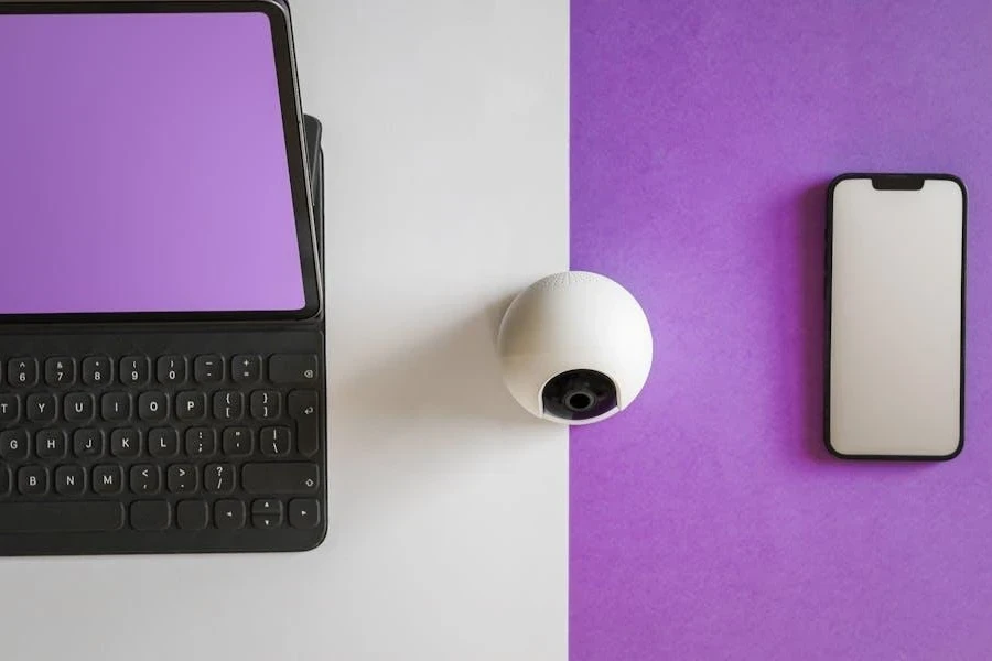 A white webcam between a laptop and phone