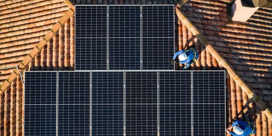 Aerial view of Two workers installing solar panels on a rooftop