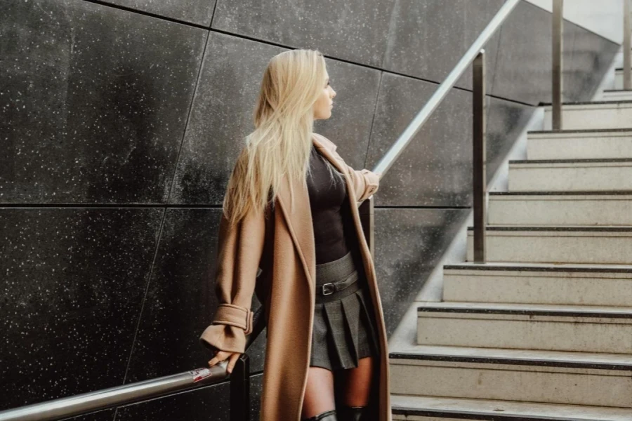 Blonde Woman in Coat Standing by Wall on Stairs