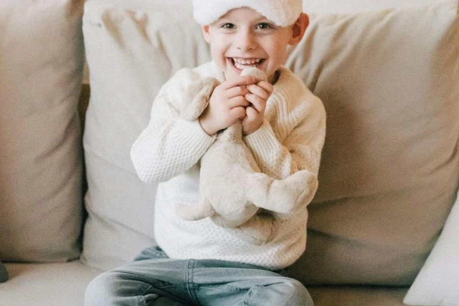 Boy In White Sweater And Blue Denim Jeans Sitting On A Couch