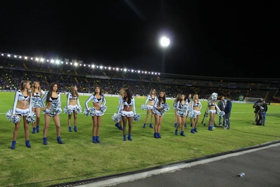 Cheerleading squad on football field with pom poms