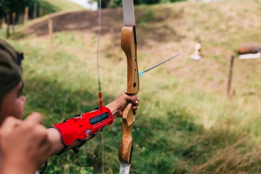 Child lining up bow to shoot at target outside