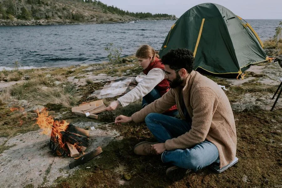 Couple starting a bonfire outside a camping tent