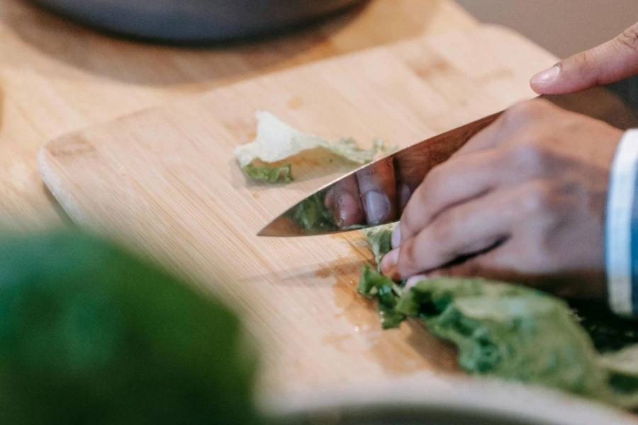 Crop Person Cutting Fresh Spinach on Chopping Board