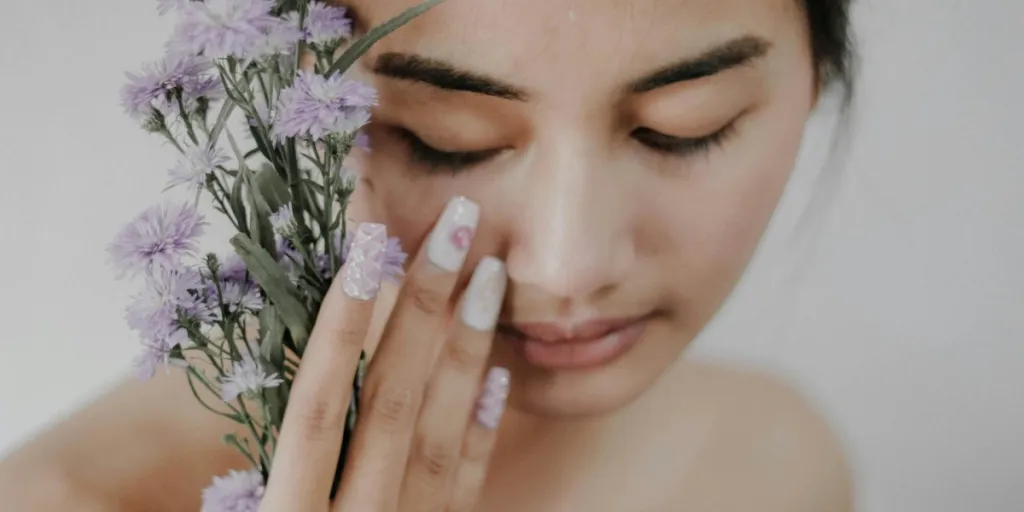 Cute lady with lovely nails holding purple flowers